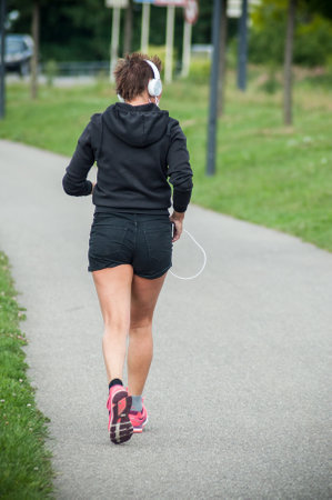 Mulhouse - France - 22 May 2018 - woman running in border channel with headphonesのeditorial素材