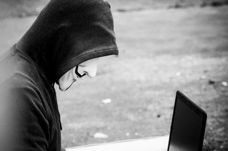 Paris - France - 19 May 2018 - portrait of man with Vendetta mask and coumputer in abandoned  factory  on vintage armchair . This mask is a well-known symbol for the online hacktivist group Anonymousのeditorial素材