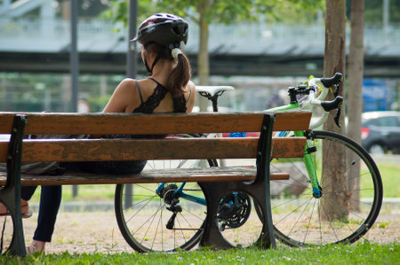 Mulhouse - France - 6 June 2018 - woman sitting on wooden bench near is bicycleのeditorial素材