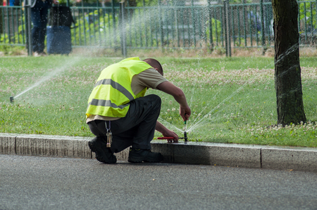 transportation company employee adjusting automatic sprinklers on tramway lineの写真素材