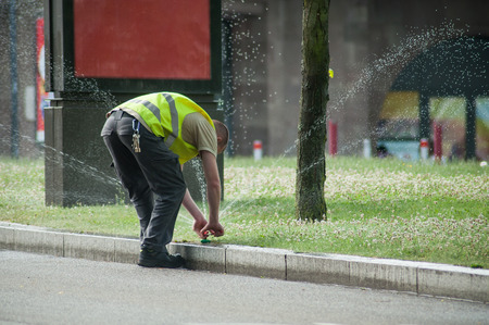 transportation company employee adjusting automatic sprinklers on tramway lineの写真素材