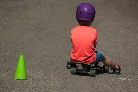 Portrait of boy sitting on skate board with helmetの写真素材