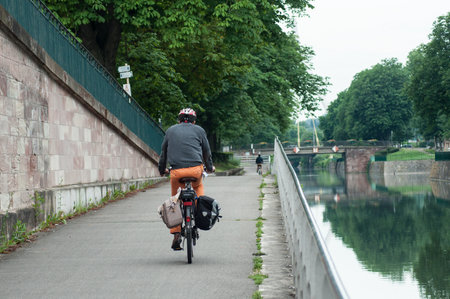 Mulhouse - France - 11 June 2018 - man rolling in bicycle with helmet in border waterのeditorial素材
