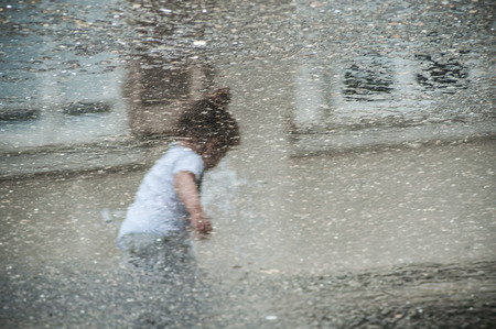Reflection of child playing with water in fountain