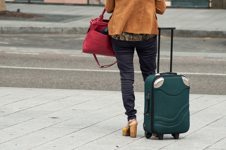 closeup of woman standing  in the street with suitcase and back pack from train stationの写真素材
