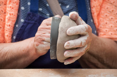 closeup of hands of old woman making clay pottery bowl in outdoor
