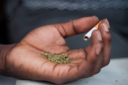 closeup of african man rolling a joint of cannabis in outdoorの写真素材