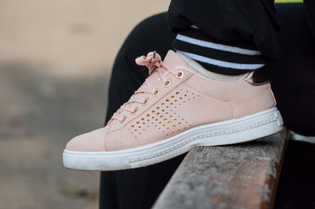 retail of  woman sitting on wooden bench with pink summer sneakers  in outdoor