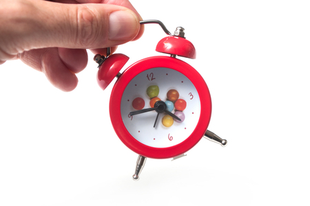closeup of red alarm clock in hand on white backgroundの写真素材
