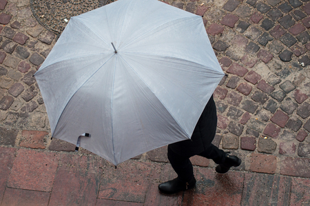 portrait of woman with grey umbrella on cobbles place in the city on top viewの写真素材