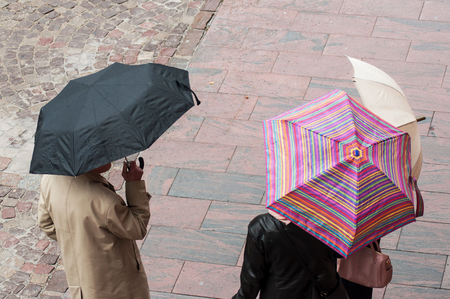 group of people standing with umbrella on cobbles place on top viewの写真素材