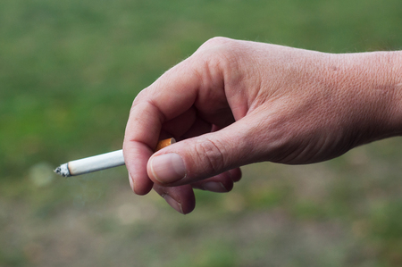 closeup of man with cigarette in hand in outdoorの写真素材