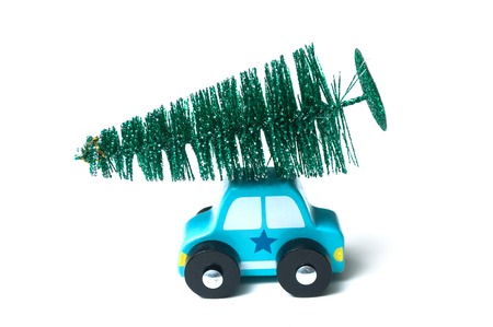 closeup of miniature wooden car with christmas tree on the roof on white backgroundの写真素材