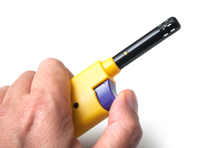 closeup of yellow lighter in hand on white backgroundの写真素材