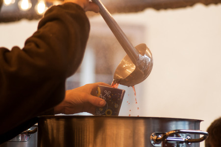 closeup of man giving a cup of mulled wine at the christmas marketの写真素材