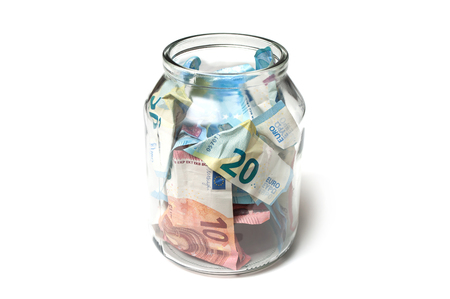 closeup of euros banknotes savings in glass container on white backgroundの写真素材