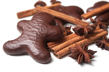 closeup of christmas gingerbread chocolate coated biscuit in shaped man with anise flower and cinnamon stick on white backgroundの写真素材