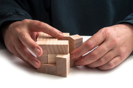 closeup of man hand with wooden puzzle  on white table backgroundの写真素材