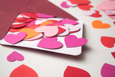 closeup of paper heart falling from envelope on white background - valentine's day concept
