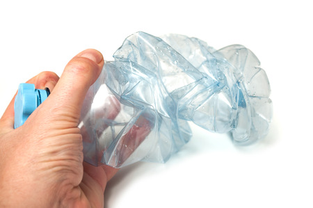 closeup of plastic bottle crushed in hand  for recycling on white background