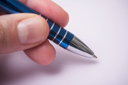 closeup of hand of man writing with blue pen on purple backgroundの写真素材