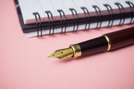 closeup of vintage pen and spirales note book on pink backgroundの写真素材