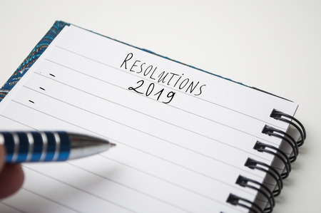 closeup of notebook on white desk with text : Resolutions 2019の写真素材