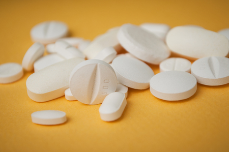 closeup of white pils on yellow backgroundの写真素材