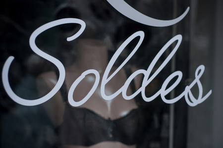 closeup of discount sign "SOLDES" in french,  the traduction of  (sales ) on window in french underwear fashion store showroom on underwear backgroundの写真素材