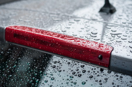 closeup of raindrops on rear lights of on black carの写真素材