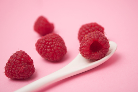 Closeup of raspberries in white spoon on pink backgroundの写真素材