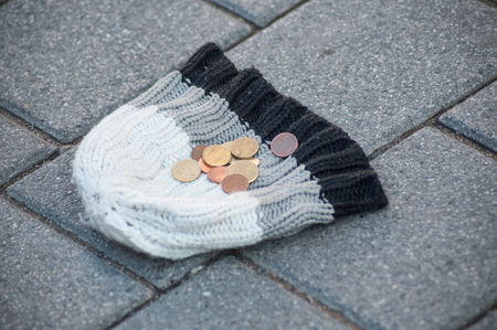 closeup of euro coins on wool hat in the street - concept povertyの写真素材