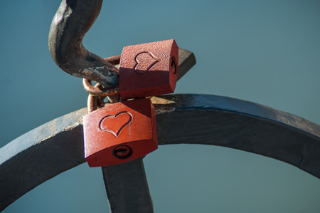 closeup of love padlock on metallic fence on blurred water backgroundの写真素材