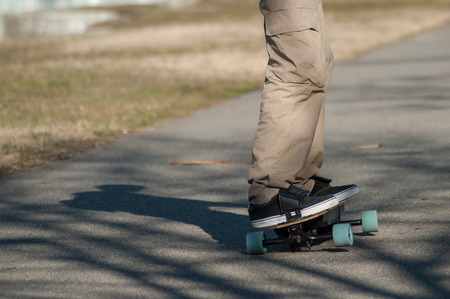 closeup of legs of man on electric skate board on the road