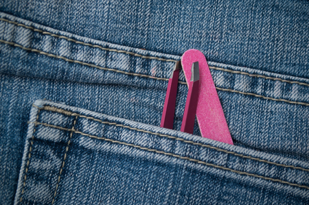 closeup of pink tweezers nail file in blue jeans pocketの写真素材