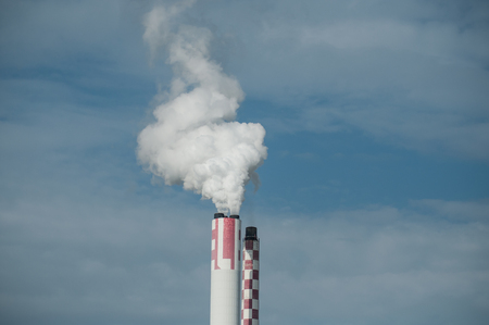 closeup  of white smoke of chemical factory chimney on blue sky backgroundの写真素材