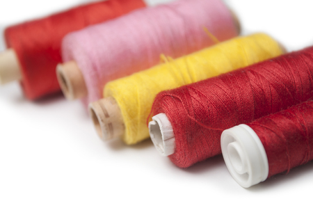 closeup of sewing thread spool bobbins on white background
