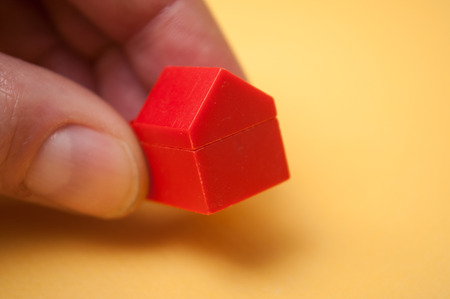 closeup of hand of man playing with plastic bricks construction on yellow backgroundの写真素材