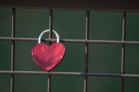 closeup of love padlock on metallic fence on blurred water backgroundの写真素材