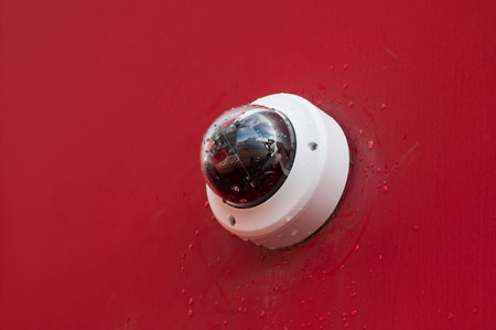 closeup of security camera on red wall backgroundの写真素材