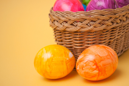 closeup of decorative painted easter eggs in wooden basket on yellow backgroundの写真素材