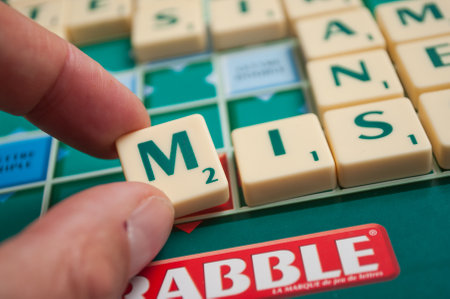 Mulhouse - France - 2 December 2018 - Closeup of plastic letters M in hand for formaing a word on Scrabble board gameのeditorial素材