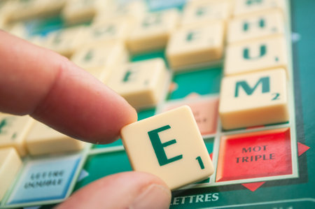 Mulhouse - France - 4 May 2019  - Closeup of plastic letters E in hand on Scrabble board gameのeditorial素材
