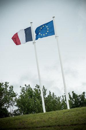 closeup of french and european flags floating on grey sky backgroundの写真素材