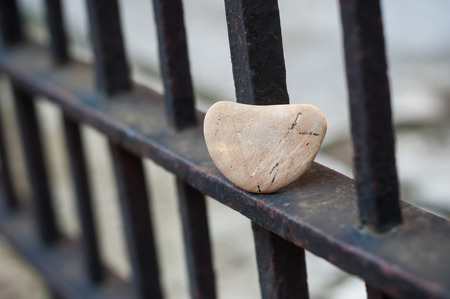 closeup of stone pebble in shaped heart on metallic grid in outdoor - Love conceptの写真素材
