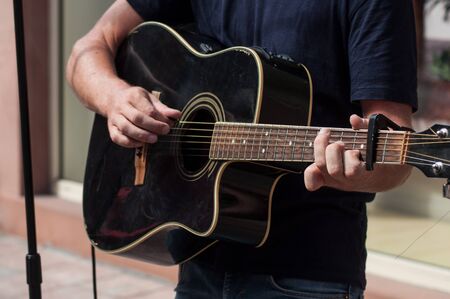 closeup of hands of musician on folk guitar in the street
