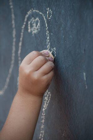 closeup of hand of child drawing with chalk on the chalkboardの写真素材