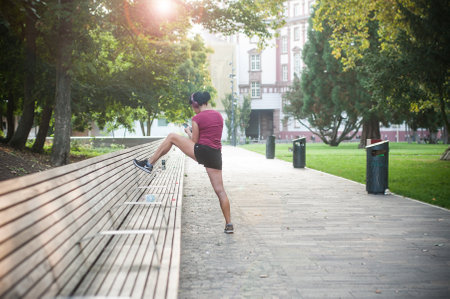 Mulhouse - France - 15 September 2019 - Portrait ofwoman making stretchin with headphone in urban parkのeditorial素材