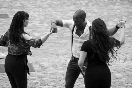 Mulhouse - France - 24 September 2019 - Portrait of black man dancing salsa with two girls in the...