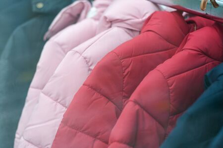 Closeup of colorful winter jackets on hangers in fashion store showroom の写真素材